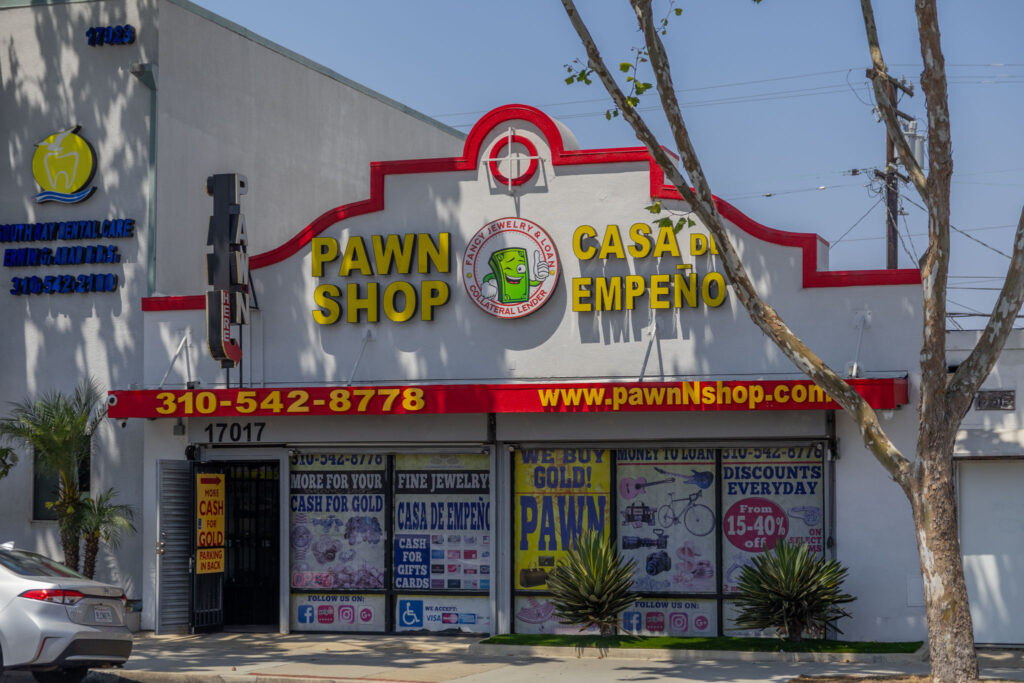 The store front of Fancy Jewelry and Loan, the image shows a clean outside environment, and the building has the store name, Number, website, and logo which features a friendly cash mascot named Benji