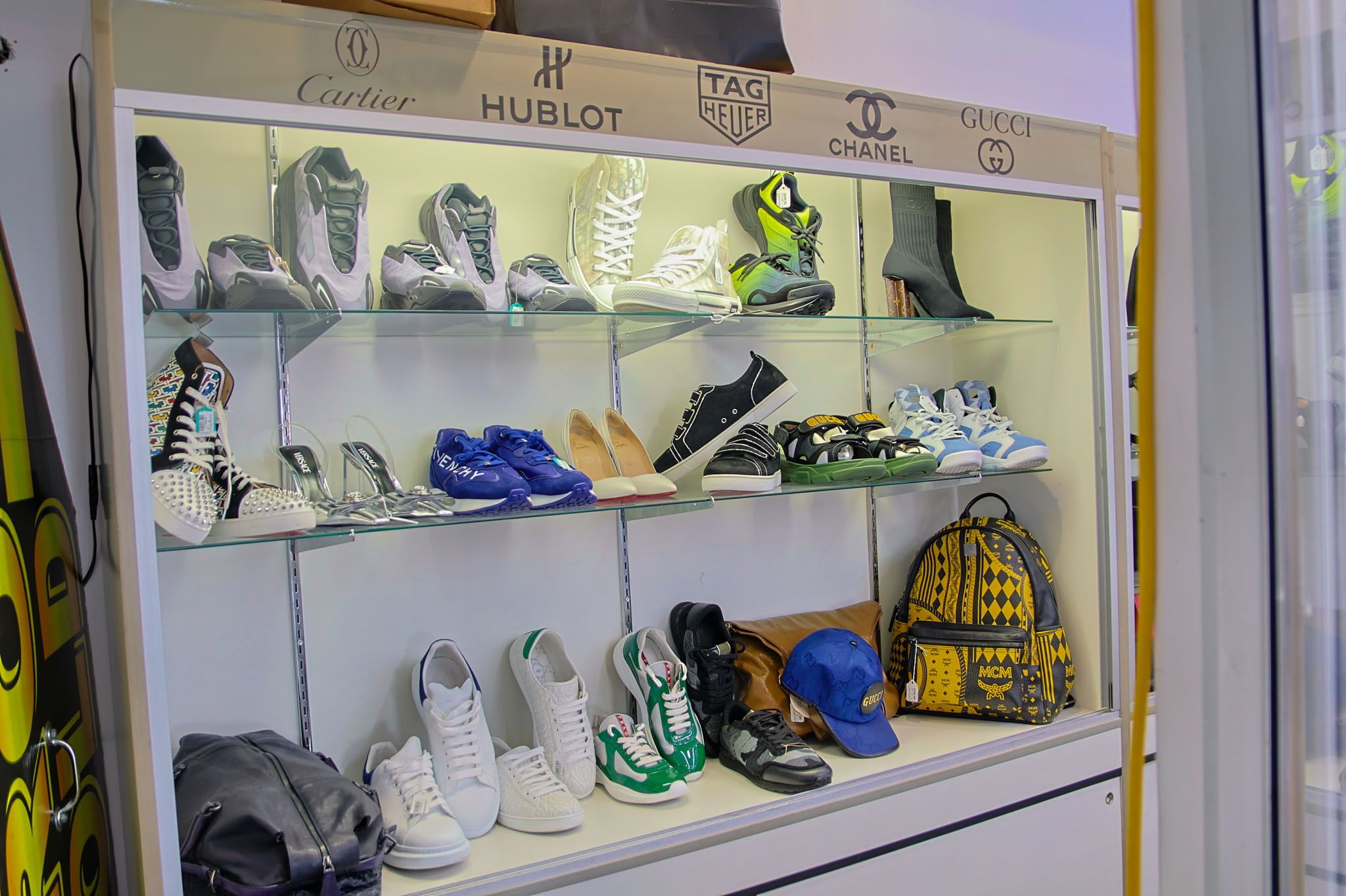 A display case in the Fancy Jewelry & Loan Pawn Shop showcasing various designer backpacks, and handbags. Brands including Gucci, Chanel, Louis Vuitton, and more.