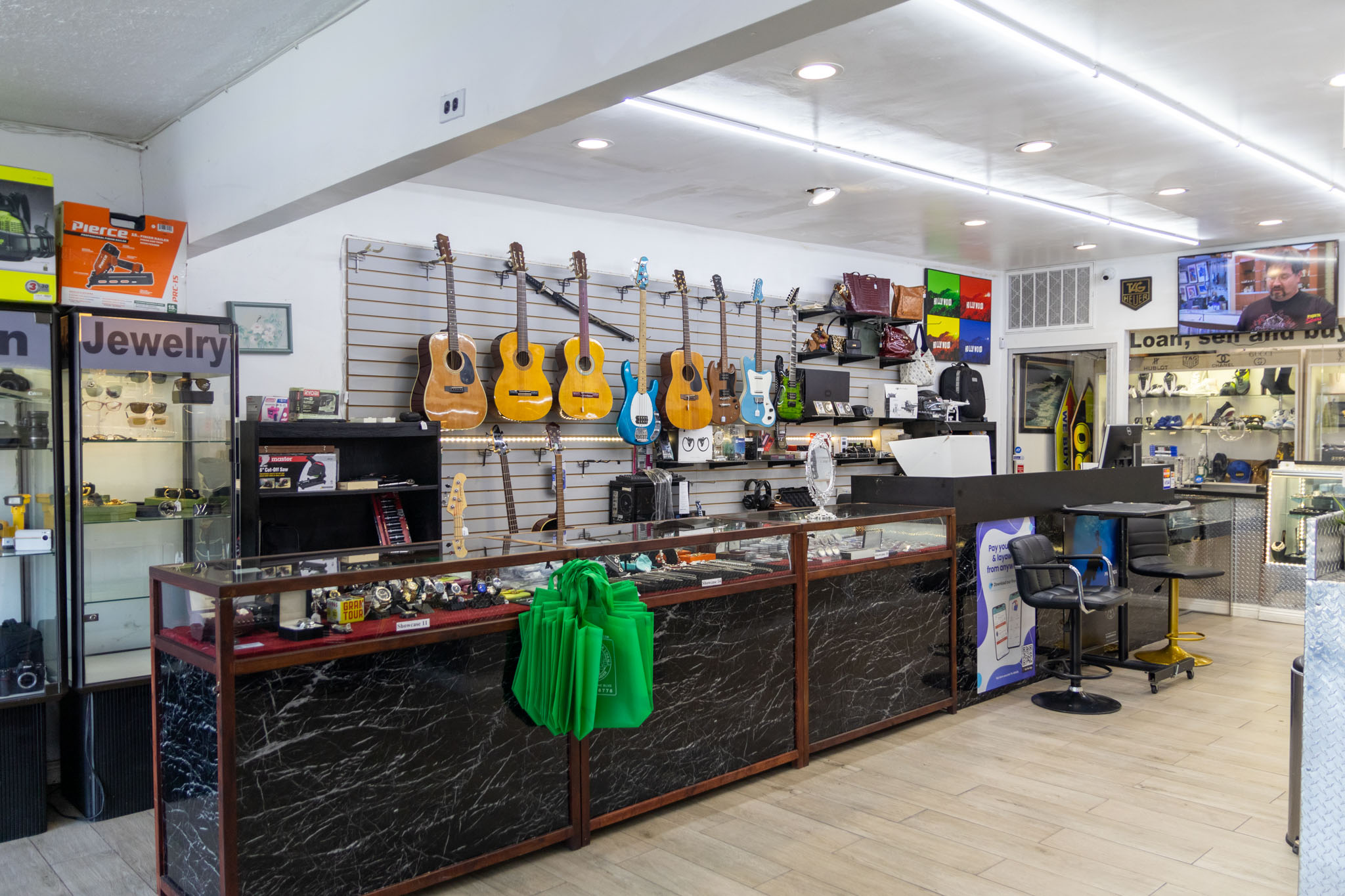 The Interior Showcase Wall of Fancy Jewelry & Loan. There is a showcase with many watches and silver coins and sports memorabilia, along with a variety of guitar and various musical instruments on the wall.