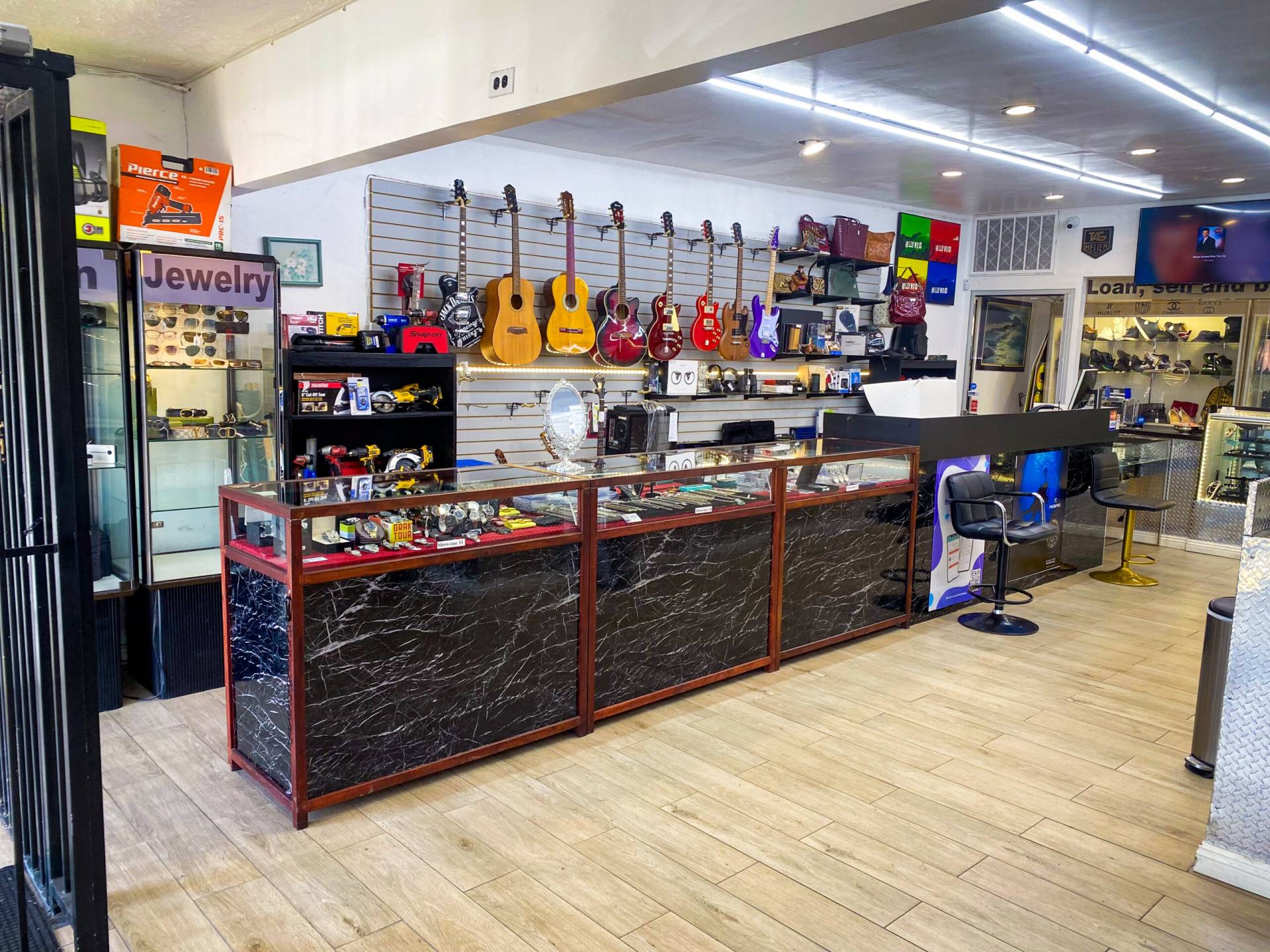 The Interior Showcase Wall of Fancy Jewelry & Loan. There is a showcase with many watches and silver coins and sports memorabilia, along with a variety of guitar and various musical instruments on the wall.